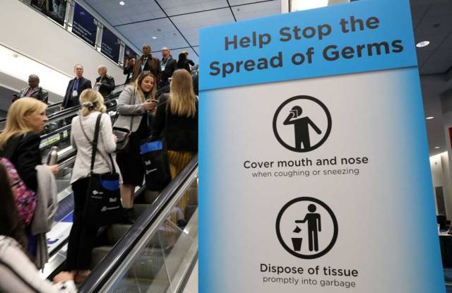  PDAC visitors pass a sign warning about the spread of germs at the Prospectors and Developers Association of Canada annual conference in Toronto on March 1, 2020.