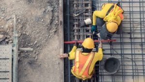 stocks to buy: construction workers work on a concrete floor
