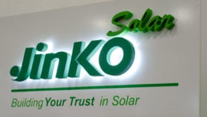 The JinkoSolar (JKS) logo displayed on a plain white wall.
