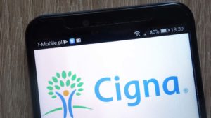 mobile phone screen with the cigna (CI) logo on it. representing healthcare stocks to buy