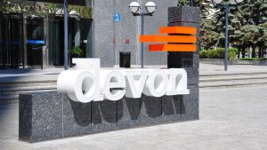 The logo for Devon Energy (DVN) is displayed on a sign outside an office.