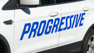 A white car with the Progressive logo written across the doors in big blue letters