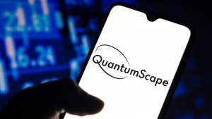 A hand holds a phone and the screen shows the QuantumScape logo