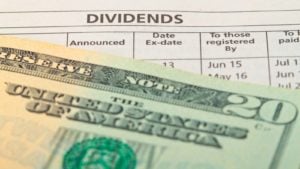 sheet of paper marked "dividends" with a $20 bill on top of it to represent dividend stocks