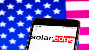 SolarEdge (SEDG) logo on phone with American flag backgroun
