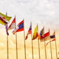 A row of flags against a yellow and blue sky