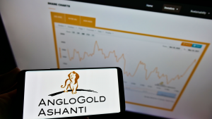 Person holding cellphone with logo of South African mining company AngloGold Ashanti Limited on screen in front of website. AU stock.