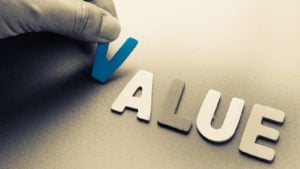 Value stocks: A hand places wooden cutouts of the letters in the word "value" on a surface.