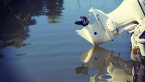 photo of white outboard motor barely touching surface of water
