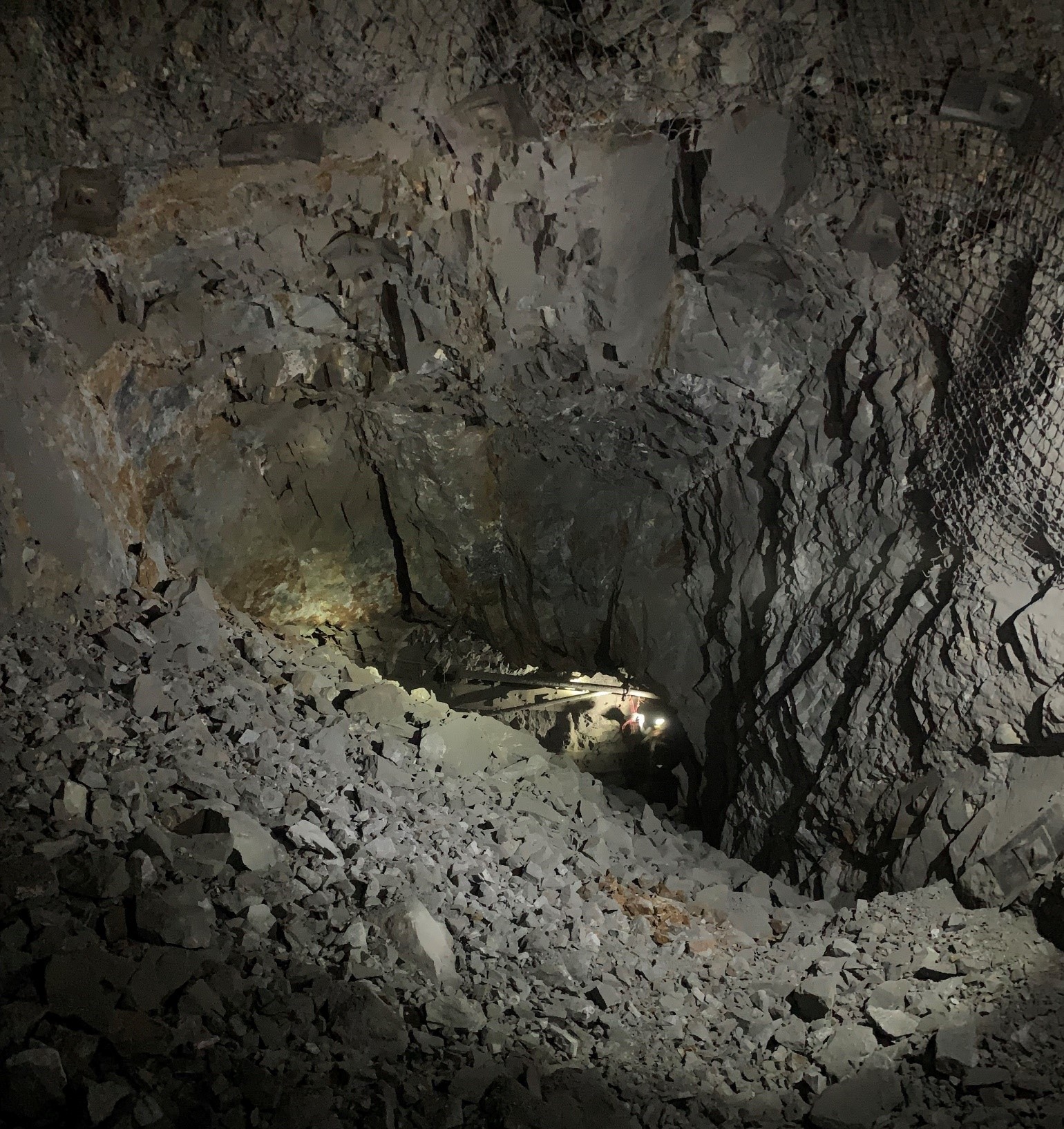 A Miner working in pre-existing infrastructure seen through the initial breakthrough from 5 Level to 6 Level